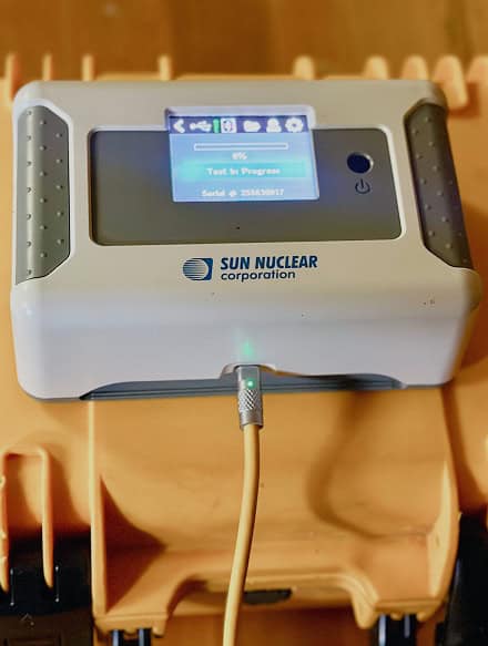 A Sun Nuclear Corporation device displays "Test in Progress" on its screen, with a yellow cable connected at the front—an essential tool for thorough CT Home Inspection.