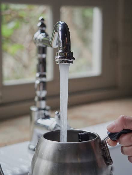 A metal kettle being filled with water from a kitchen faucet, ready for your next cup—just one of the details Anchor Home Inspection in CT will check during your home evaluation.